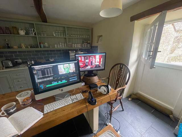 Two screens on a kitchen table - an ad hoc editing station, with light coming through the stable door on the right